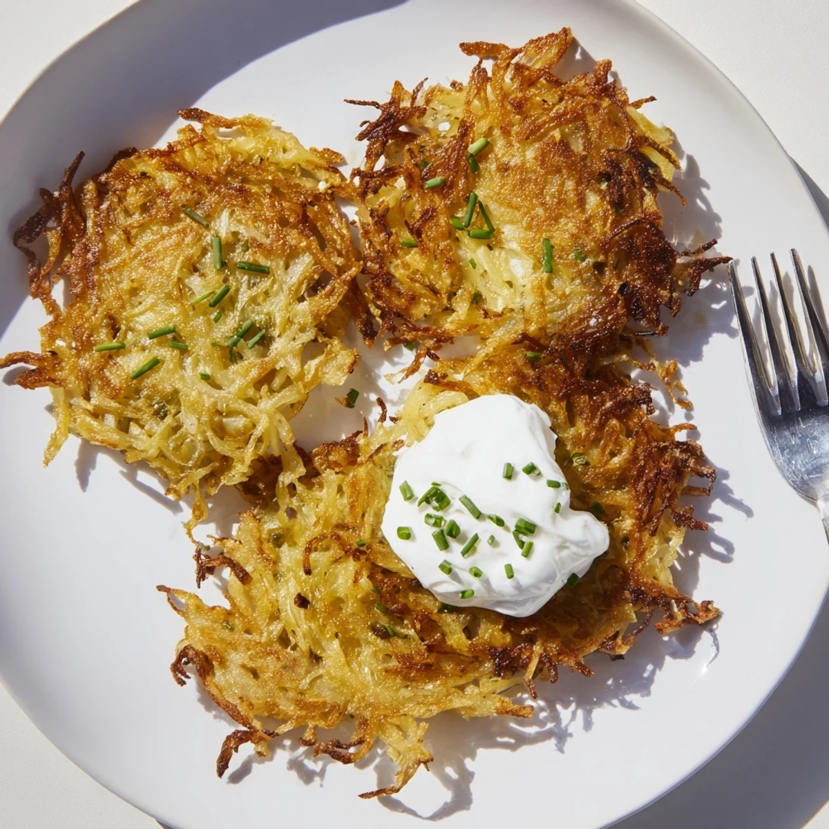 Golden brown potato pancakes served hot, perfect for brunch with sour cream.  