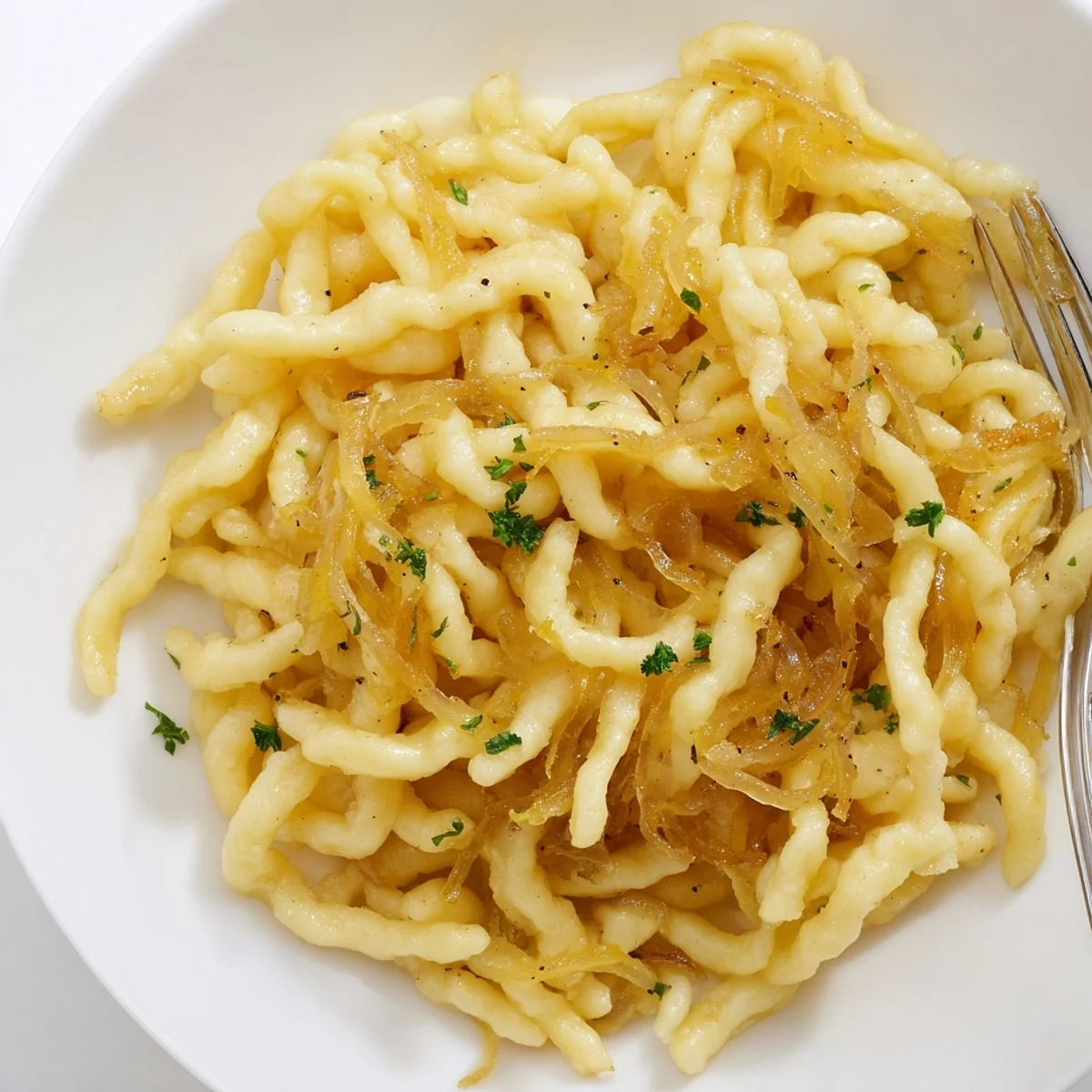 Hausgemachte Spaetzle mit goldbraunen Zwiebeln – eine köstliche, deutsche Spezialität.  