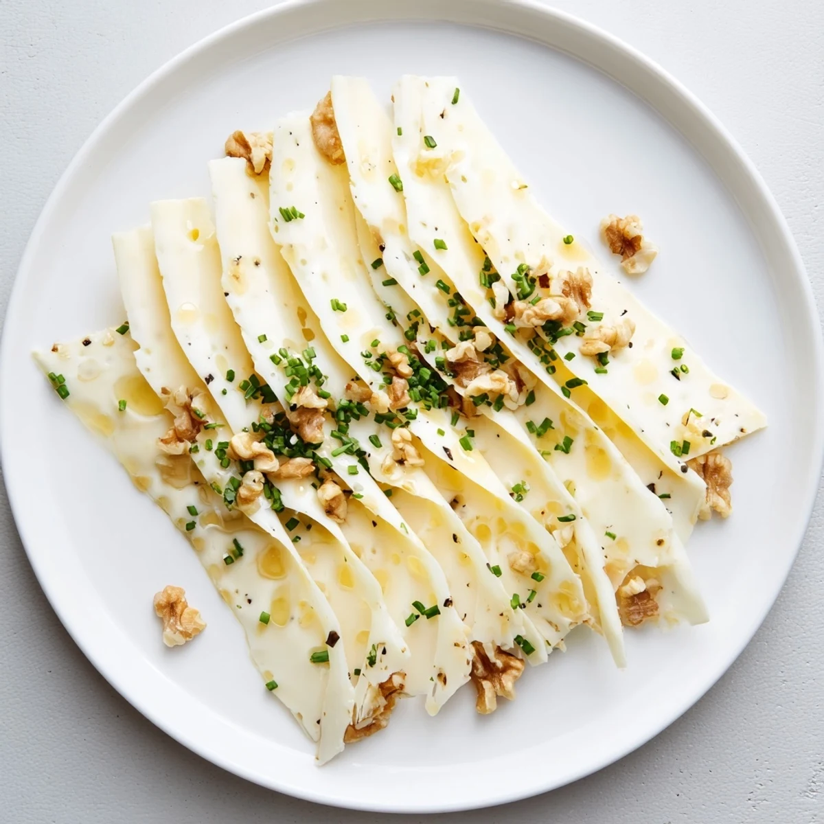 Appetizing close-up of a Swiss cheese slices fan, garnished with fresh chives, a quick and easy appetizer.