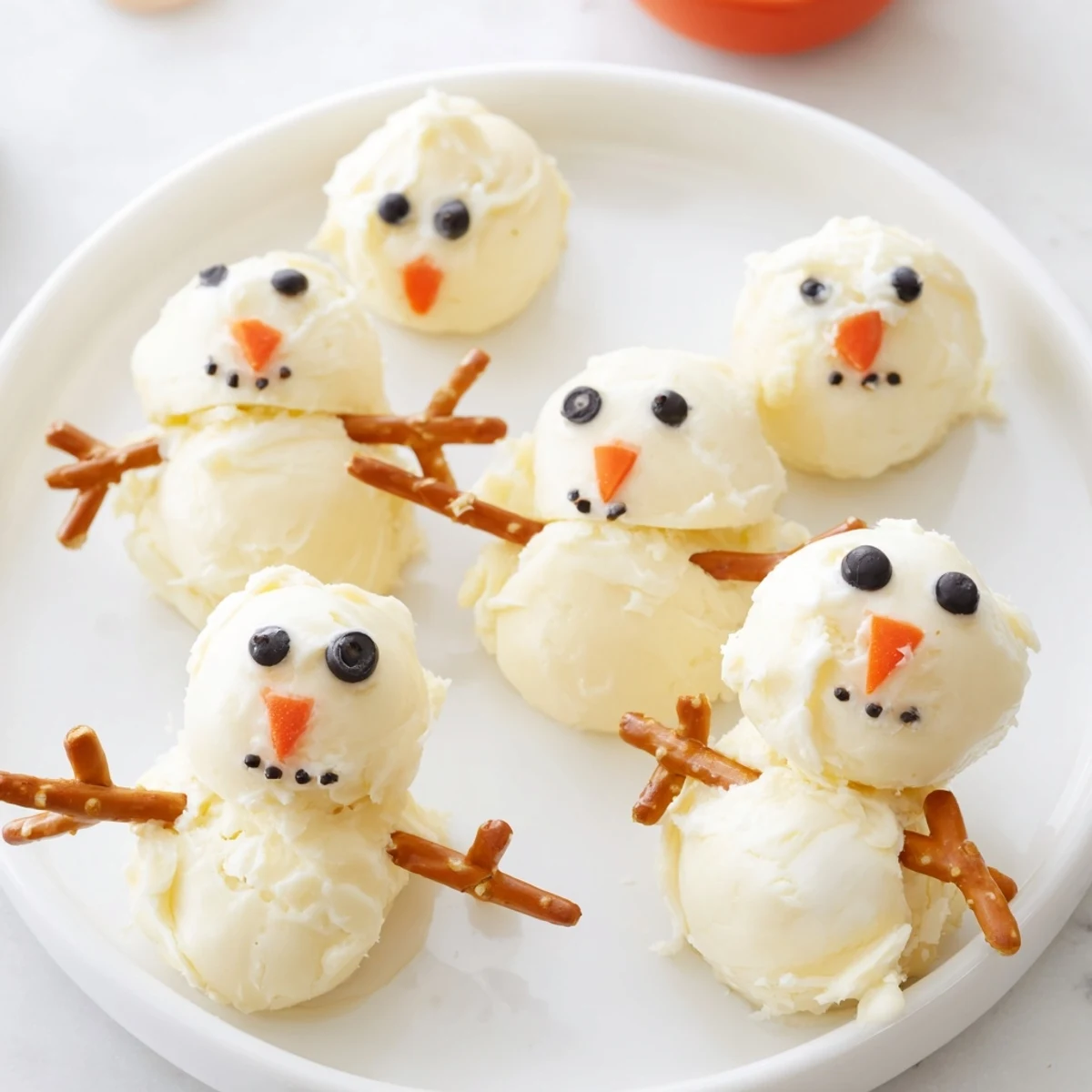 Melted Snowman Cheese Bites, a festive appetizer with creamy cheese and black olive details.