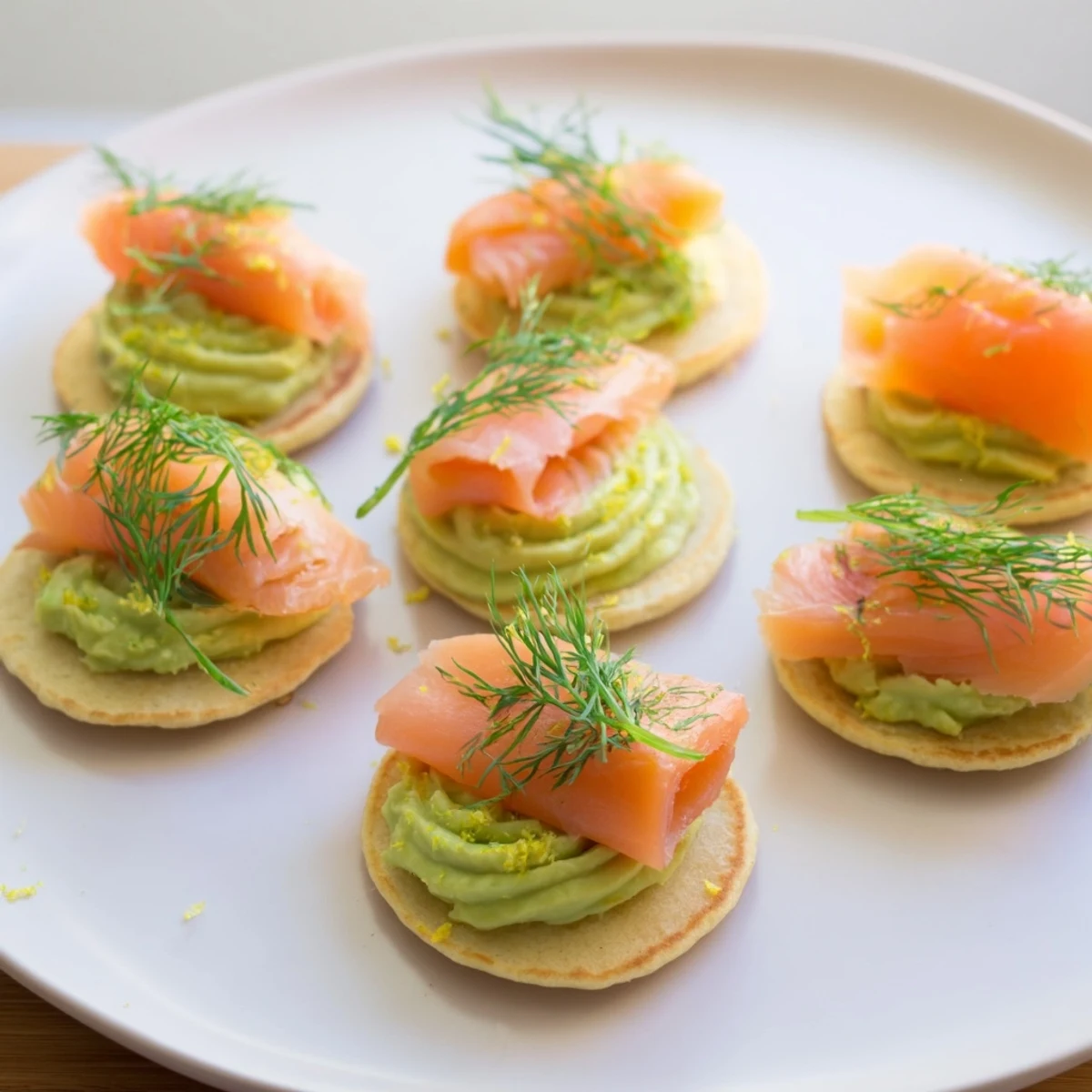 Fluffy quark blinis topped with smoked salmon, creamy avocado, and fresh dill ready to serve.