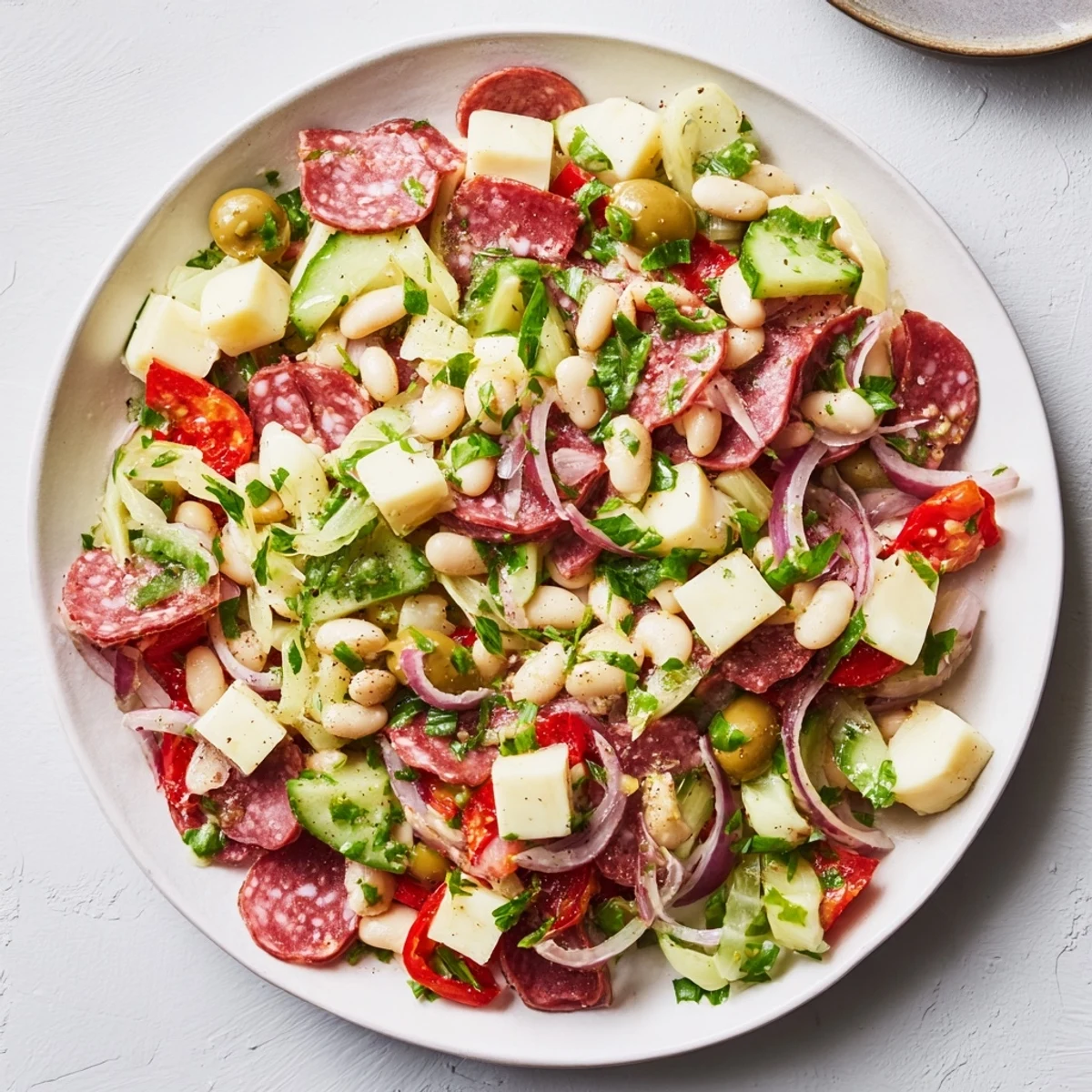 Italian Antipasto Bean Salad: A colorful bowl of chilled salad with salami, provolone, and fresh tomatoes.