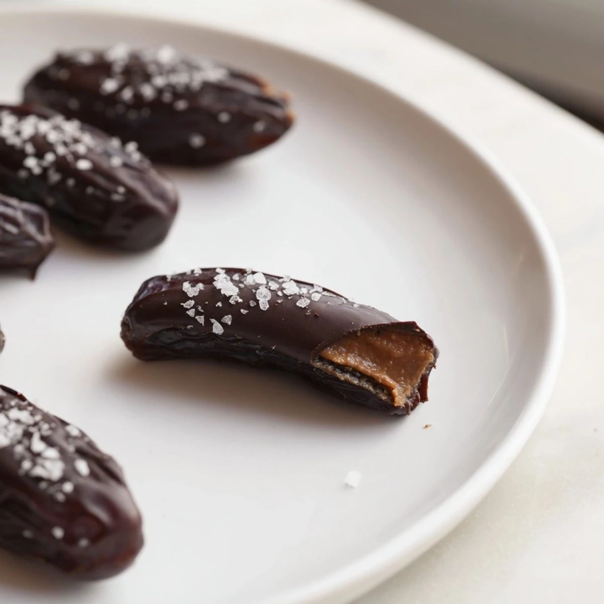 Rich dark chocolate-covered Chocolate Peanut Butter Dates, a perfect snack with flaky sea salt sprinkled on top.