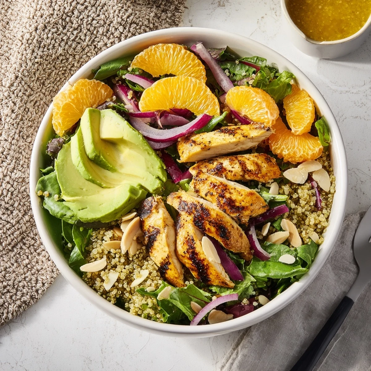 Grilled herb chicken and avocado slices over quinoa and greens, topped with orange segments for a fresh Citrus Herb Chicken Salad Bowl.