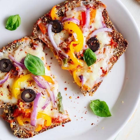 Golden, bubbly, cheesy Marble Rye Pizza Toast topped with colorful bell peppers and savory olives.