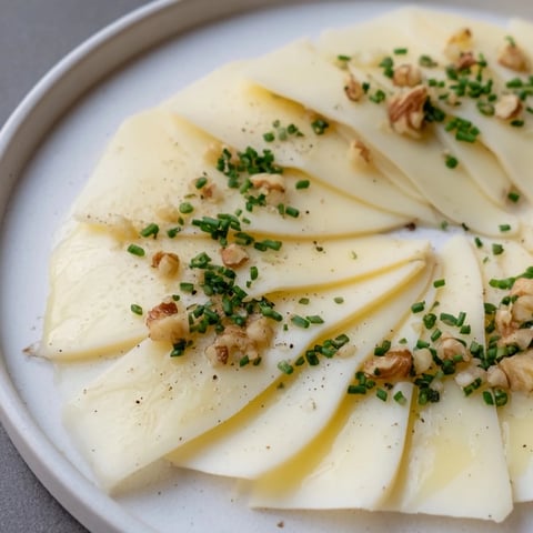 Elegant appetizer photo: A fan of Swiss cheese slices, ready to be enjoyed with chives and optional walnuts.