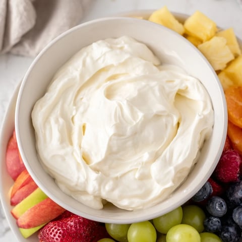 Creamy cream cheese fruit dip in a decorative bowl, surrounded by fresh, vibrant fruit for dipping.