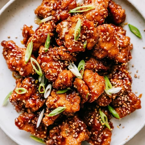 Sizzling Sweet and Spicy Sriracha Honey Chicken in a pan, coated with a glistening, flavorful glaze.
