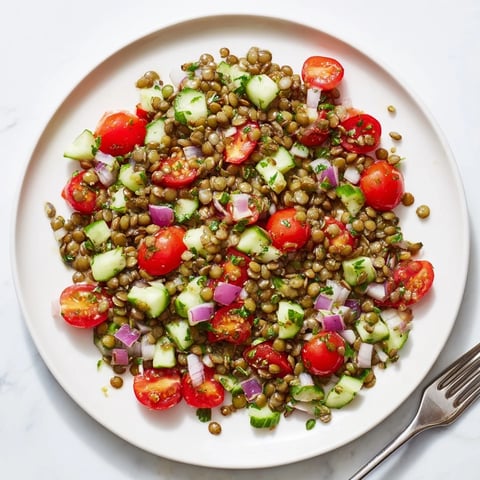 Lentil salad glistening with a vibrant mustard vinaigrette, featuring fresh tomatoes and cucumbers.