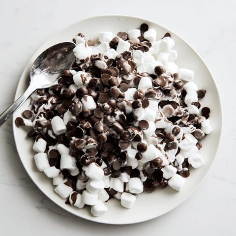 Ein Teller voller klebriger, geschmolzener Schokoladenstückchen und Marshmallows, ein schneller süßer, einfacher Genuss.