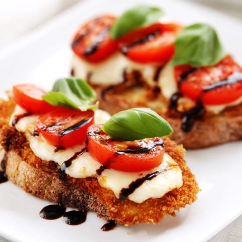 Goldener, panierter Hähnchenschnitzel sandwich mit geschmolzenem Mozzarella und frischem Basilikum auf Ciabatta.