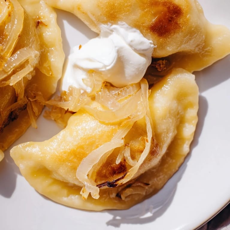 A close-up of delicious, hot Polish pierogi, showcasing the creamy filling and golden crust.