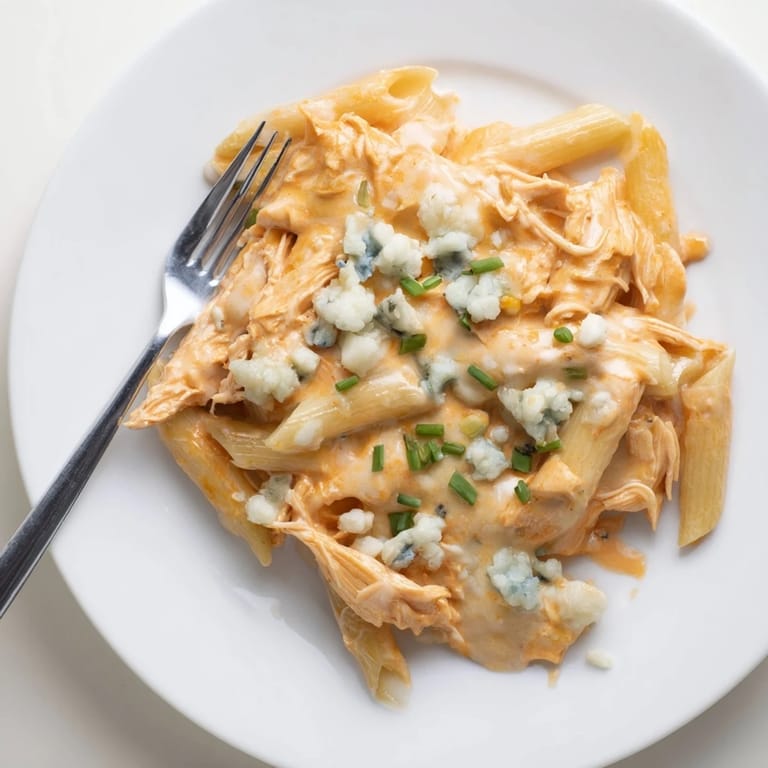 A hearty skillet of Buffalo Chicken Pasta with creamy sauce, ready to serve with crisp celery sticks on the side.