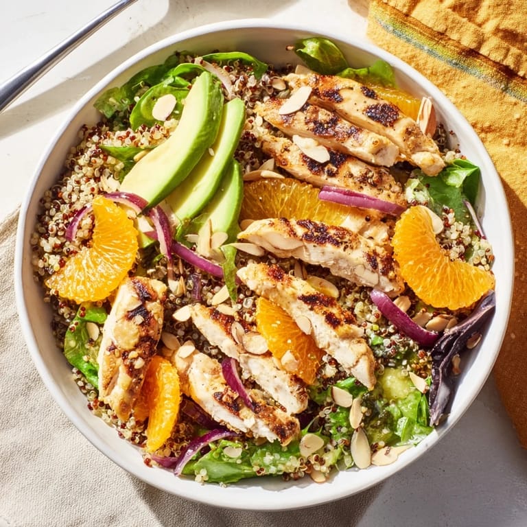 A vibrant bowl of Citrus Herb Chicken Salad with quinoa, avocado, and grilled chicken, drizzled with zesty orange vinaigrette.